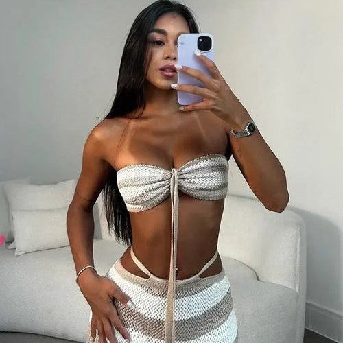 Woman taking a mirror selfie wearing a white and gray striped outfit.